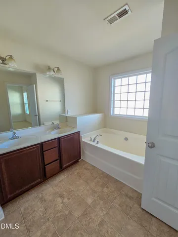a spacious bathroom with a tub sink and mirror