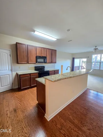 a large kitchen with stainless steel appliances granite countertop a stove a sink a refrigerator and a granite countertops with wooden floor