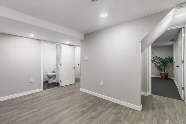 an empty room with wooden floor and a hallway