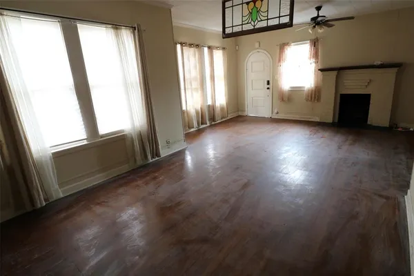 an empty room with windows and fireplace
