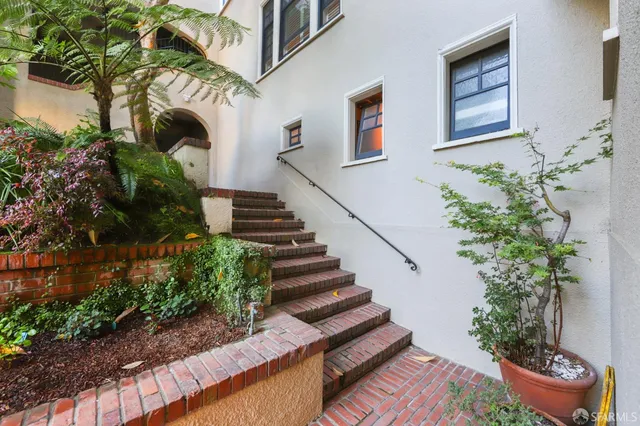 a view of a house with wooden stairs and potted plants