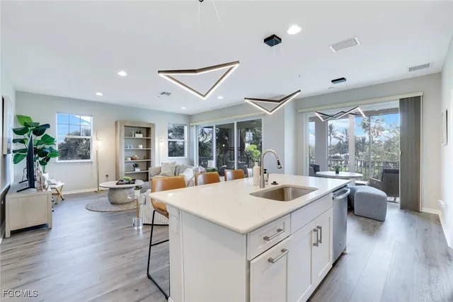 a view of living room kitchen with stainless steel appliances granite countertop a sink and wooden floor