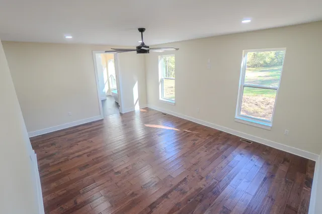 a view of an empty room with wooden floor and a window