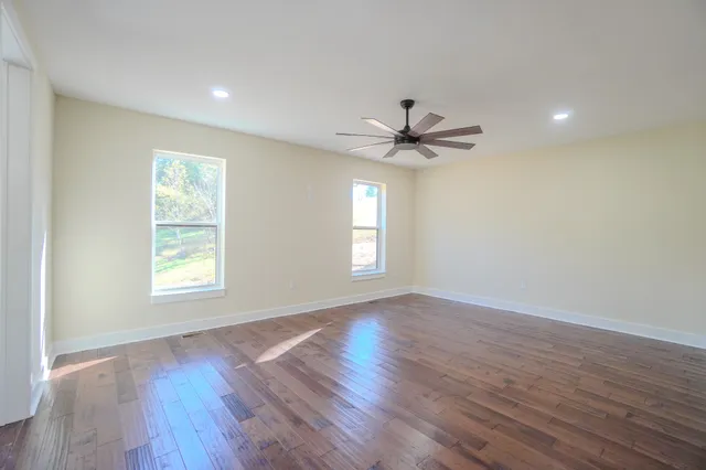 a view of an empty room with a window and wooden floor