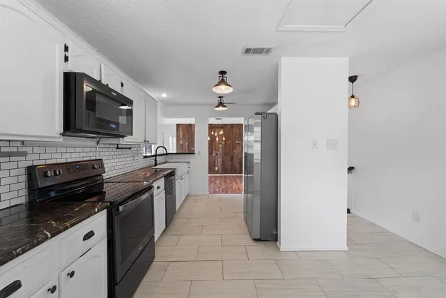 a modern kitchen with stainless steel appliances granite countertop a stove cabinets and a sink