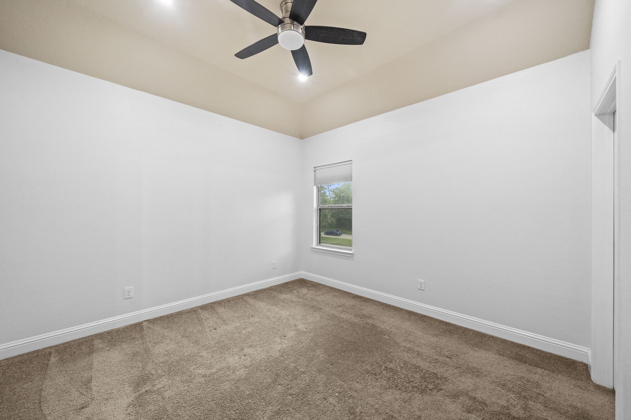 14215 Spindle Arbor Road Cypress, TX 77429 - Photo 28 of 47 This room features neutral walls with a beige ceiling, a modern ceiling fan, and plush carpet flooring. A single window allows natural light, creating a cozy and inviting space.