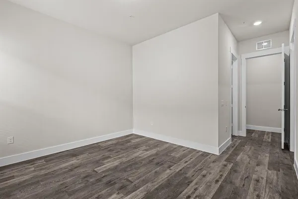 a view of an empty room with wooden floor and closet