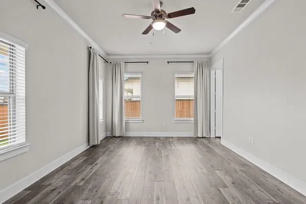 a view of empty room with wooden floor and fan