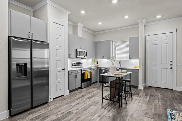 a kitchen with stainless steel appliances a refrigerator a stove a sink dishwasher and a dining table with wooden floor