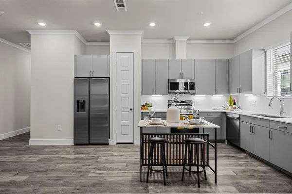 a kitchen with stainless steel appliances granite countertop a table chairs sink refrigerator and cabinets