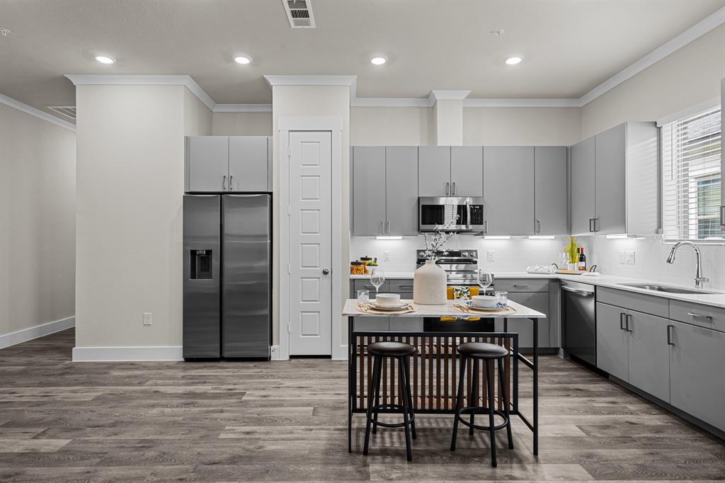 3283 Ganzer Road West, Unit 1105B Denton, TX 76207 - Photo 7 of 37 a kitchen with stainless steel appliances granite countertop a table chairs sink refrigerator and cabinets