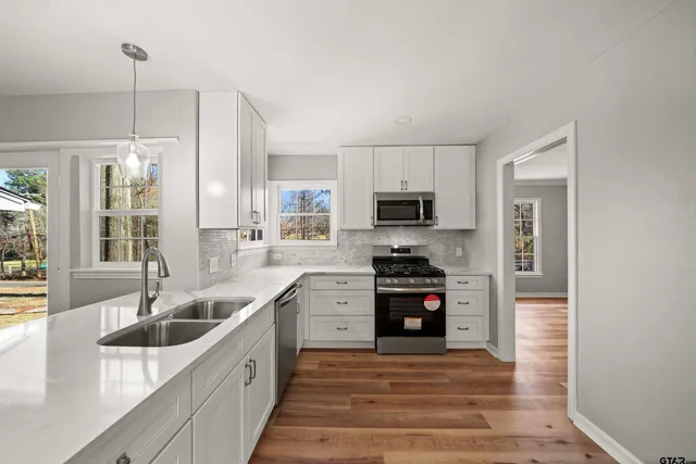 a large kitchen with stainless steel appliances granite countertop a sink and dishwasher a stove top oven with wooden floor