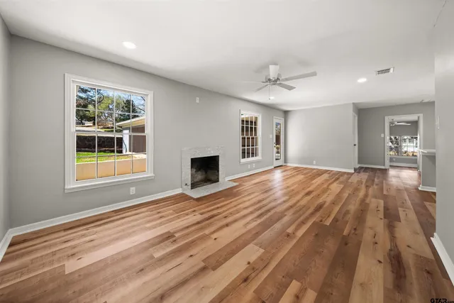 a view of empty room with wooden floor and fan