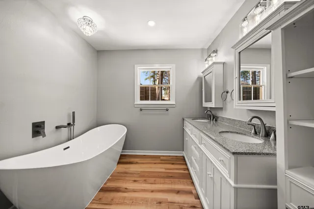 a bathroom with a granite countertop sink mirror and bathtub