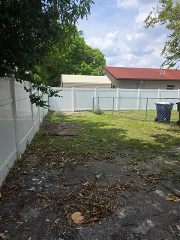 a view of a backyard with barn plants and large tree