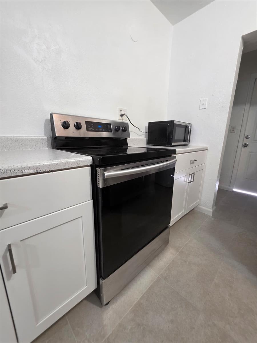 511 Northwest 4th Avenue, Unit 2 Hallandale Beach, FL 33009 - Photo 10 of 28 a kitchen with a stove and white cabinets