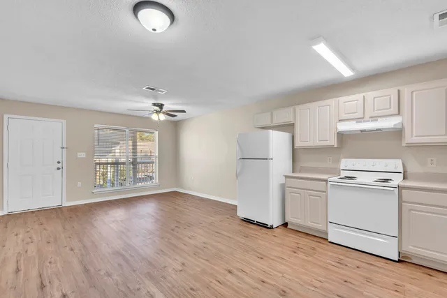 wooden floor in an empty room with a kitchen