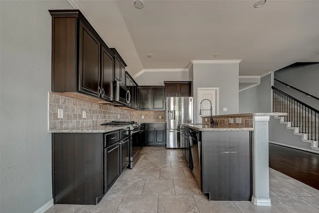 a kitchen with stainless steel appliances granite countertop a stove top oven a sink a counter space and cabinets