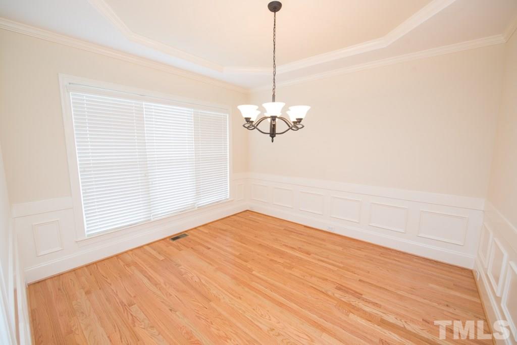 4528 Deer Stream Lane Raleigh, NC 27603 - Photo 6 of 25 Formal dining room with tray ceiling, wainscoting, crown molding, transom windows above the doorway and refinished hardwoods.