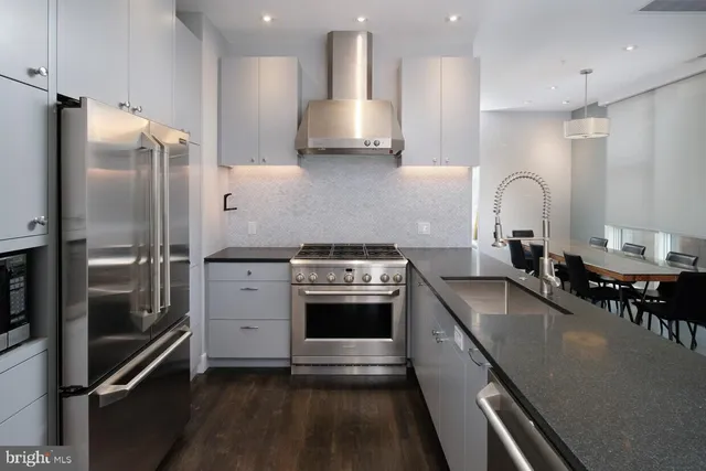 a kitchen with stainless steel appliances granite countertop a sink a stove and a refrigerator