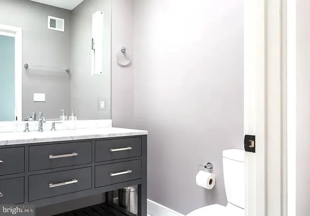 a bathroom with a granite countertop sink mirror and toilet