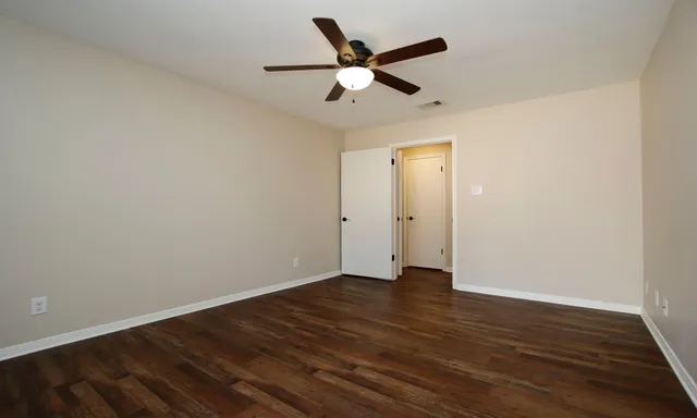 an empty room with wooden floor and ceiling fan