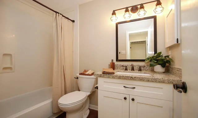a bathroom with a granite countertop toilet sink and mirror