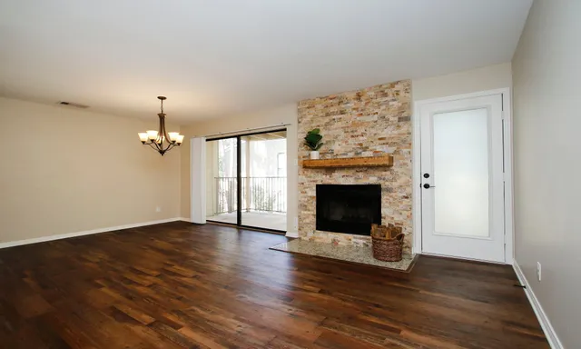 an empty room with wooden floor fireplace and windows