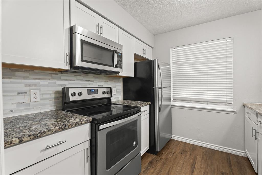 429 Johnson Street, Unit 10 Longview, TX 75602 - Photo 2 of 12 a kitchen with granite countertop cabinets stainless steel appliances and wooden floor