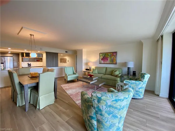 a living room with furniture kitchen view and a wooden floor