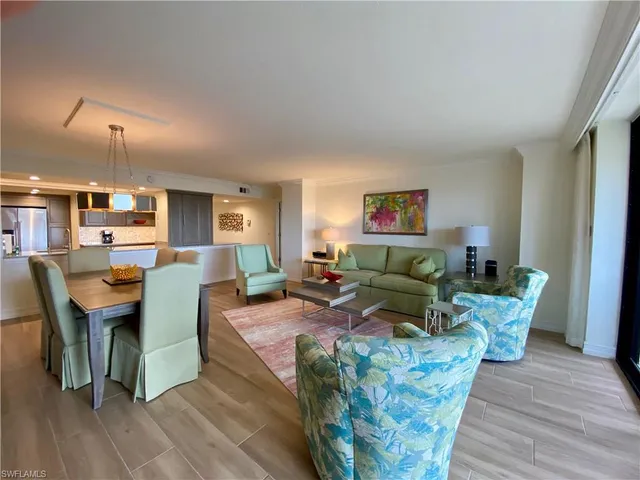 a living room with furniture kitchen view and a wooden floor