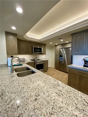 a kitchen with stainless steel appliances kitchen island granite countertop a sink stove and refrigerator