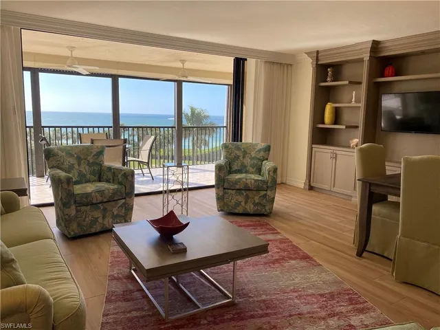 a living room with furniture a flat screen tv and a floor to ceiling window
