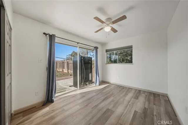 an empty room with wooden floor fan and windows