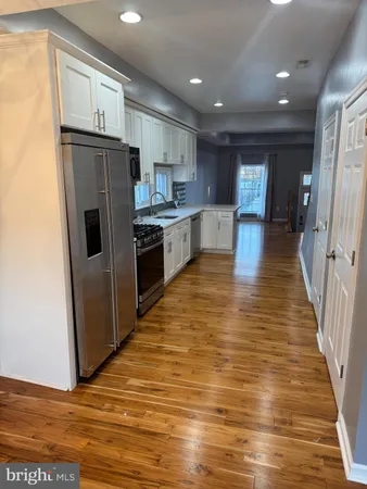 a view of a kitchen with refrigerator and wooden floor