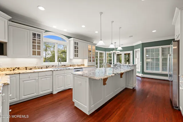 a kitchen with stainless steel appliances a stove a sink dishwasher and white cabinets with wooden floor