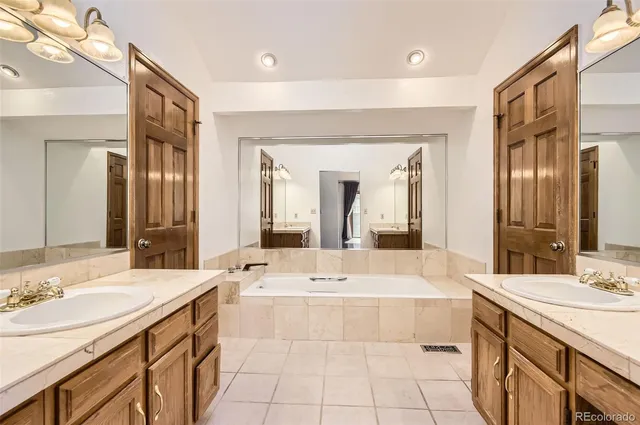 a bathroom with a double vanity sink mirror and bathtub