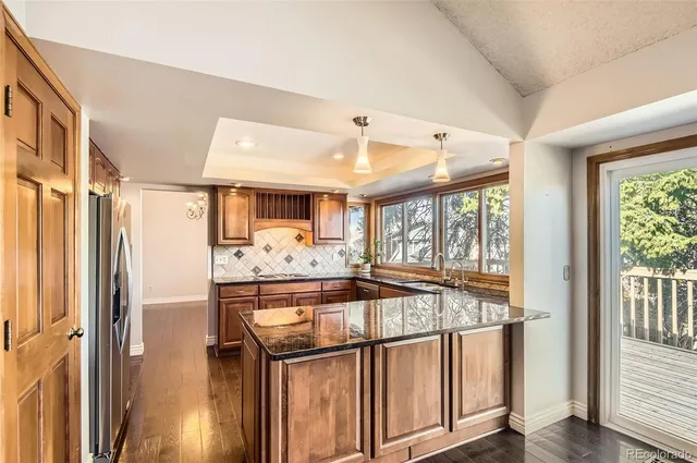 a kitchen with stainless steel appliances granite countertop a refrigerator and a view of living room