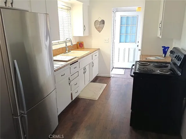 a kitchen with granite countertop a sink dishwasher a dining table and chairs with wooden floor