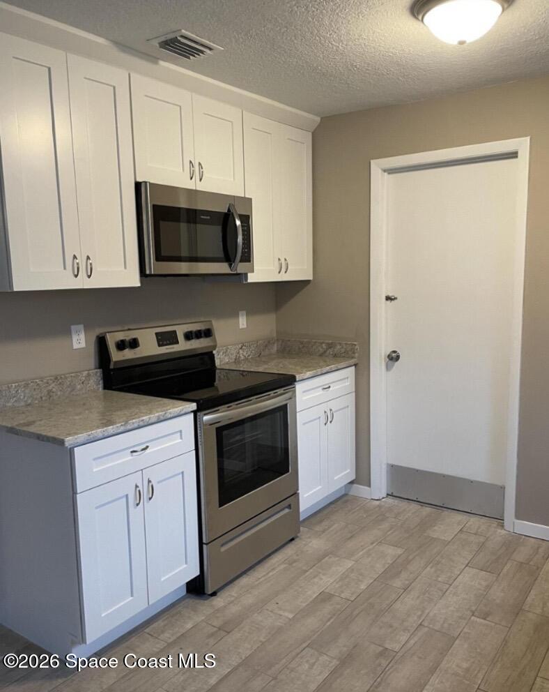 830 Angela Avenue, Unit B Rockledge, FL 32955 - Photo 3 of 9 a kitchen with white cabinets and white appliances