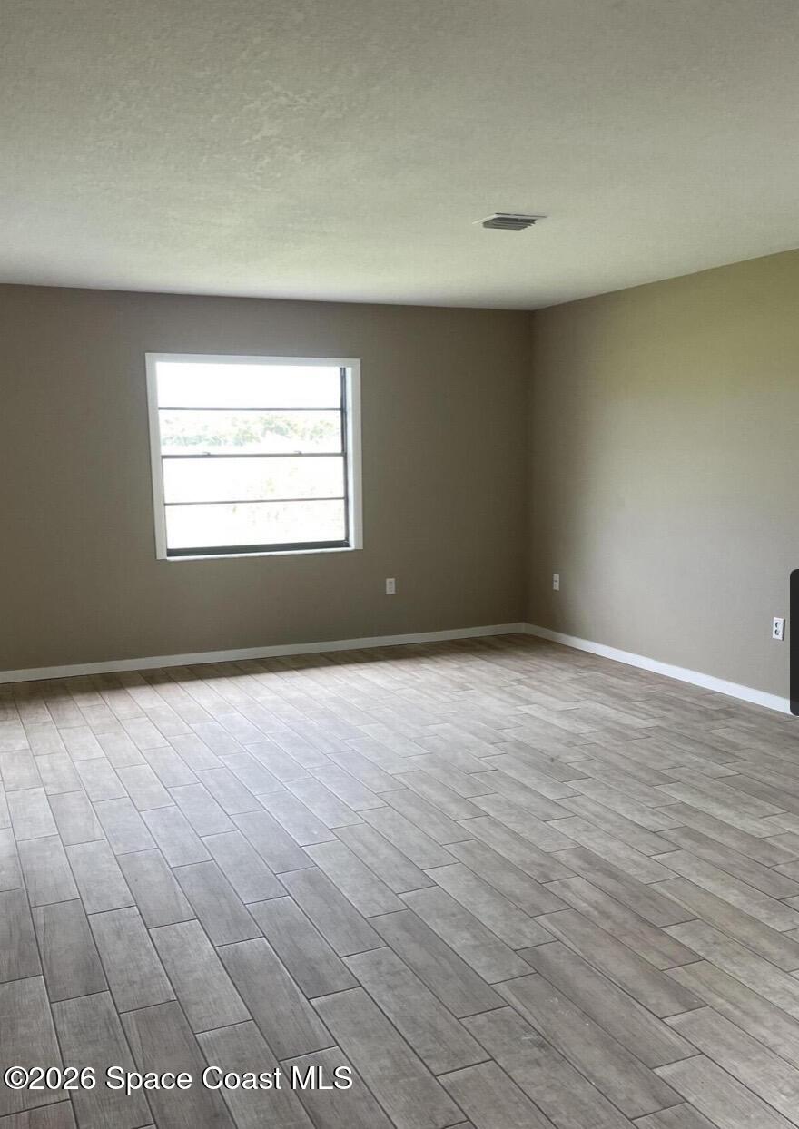 830 Angela Avenue, Unit B Rockledge, FL 32955 - Photo 9 of 9 an empty room with wooden floor and windows