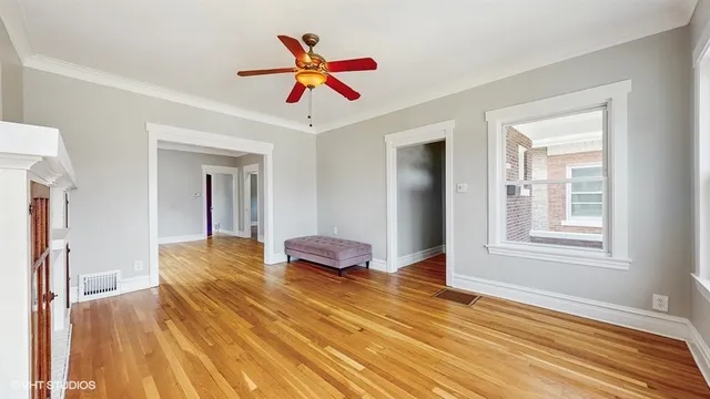 a bedroom with wooden floor and a ceiling fan