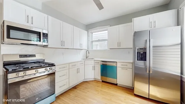 a kitchen with cabinets stainless steel appliances and a wooden floor