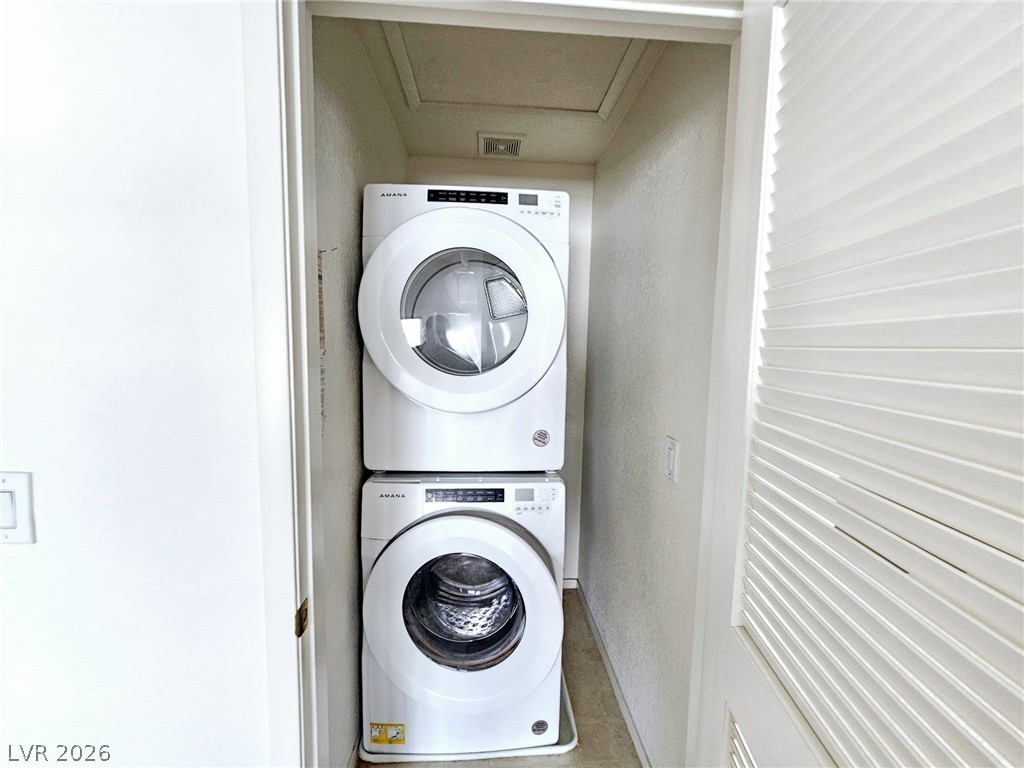 1663 Lefty Garcia Way Henderson, NV 89002 - Photo 20 of 31 A compact laundry space offers efficient stacked appliances, perfect for streamlined living.