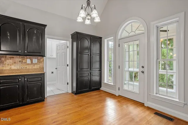 an empty room with wooden floor cabinet and windows