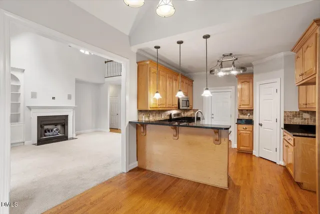 a view of a kitchen with a sink a refrigerator a fireplace and a wooden floor