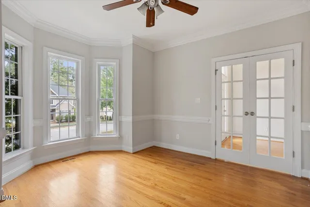 an empty room with wooden floor and windows