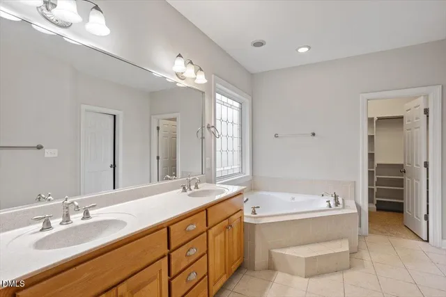 a bathroom with a granite countertop tub sink and mirror