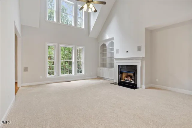 an empty room with a fireplace fan and windows