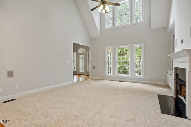 an empty room with windows and fireplace